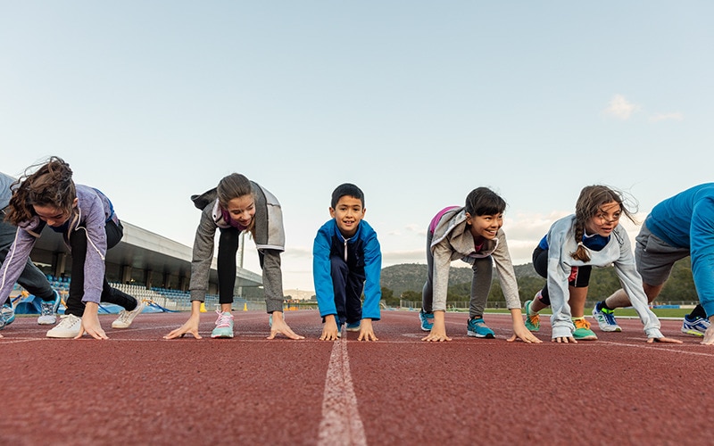 Crianças da escola preparadas para correr numa pista desportiva
