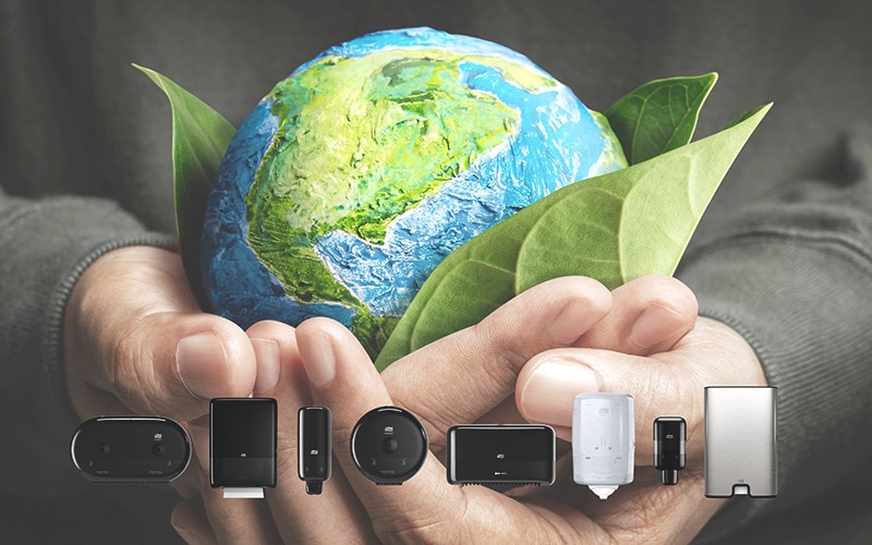 Hand holding the earth and in front some Tork dispensers