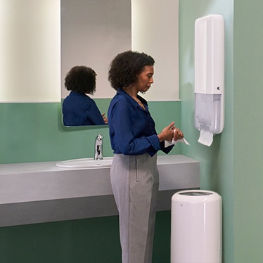 En kvinde tager et papirhåndklæde fra en dispenser