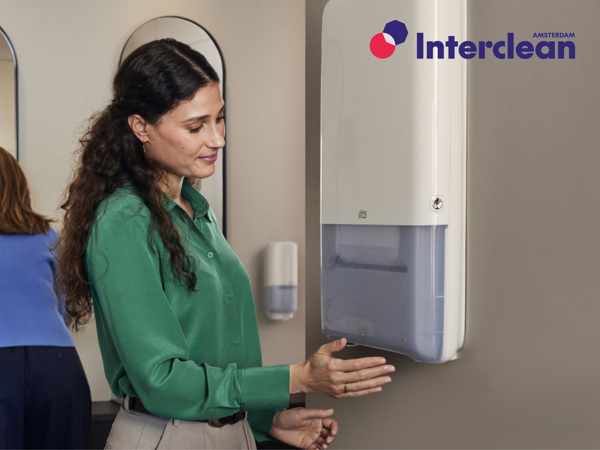 Woman using automatic paper towel dispenser in modern restroom. Interclean Amsterdam logo is present. Woman using automatic paper towel dispenser in modern restroom. Interclean Amsterdam logo is present.