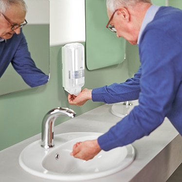 En ældre mand, der tager sæbe fra en dispenser