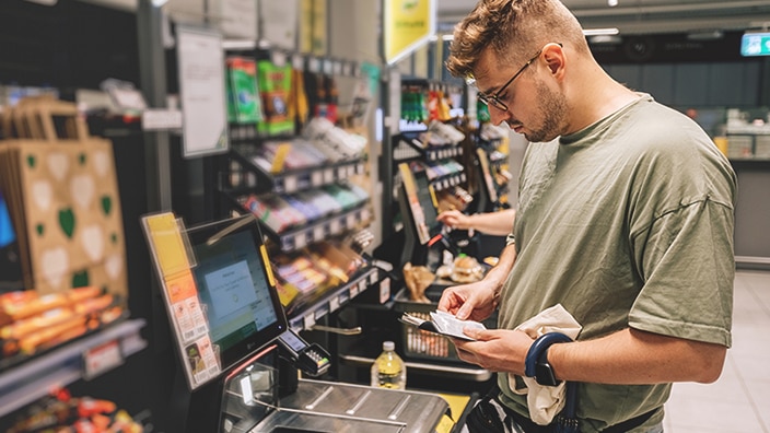 A man standing in front of a checkout register A man standing in front of a checkout register