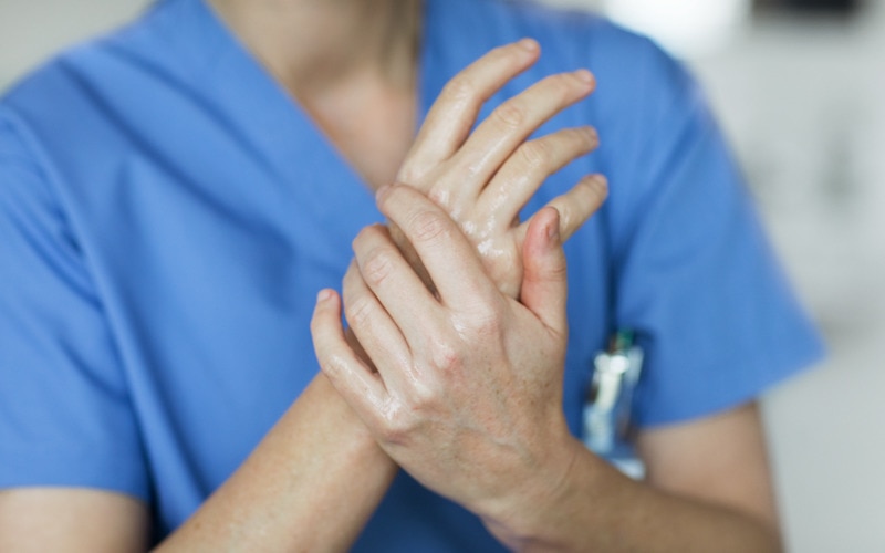 Krankenschwester cremt ihre Hände mit Feuchtigkeitscreme ein