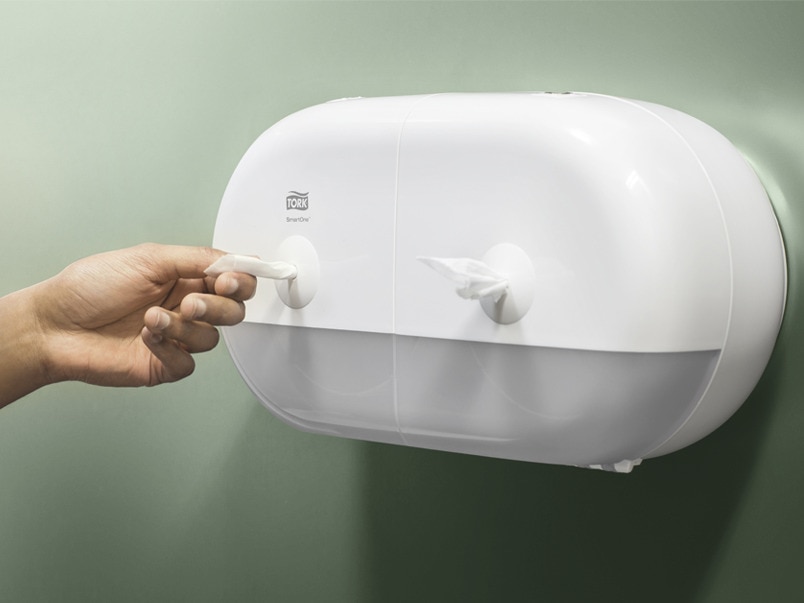 Hand pulling a paper towel from a SmartOne dispenser