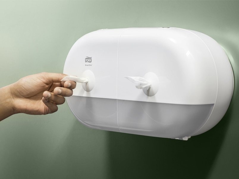Hand pulling a paper towel from a SmartOne dispenser