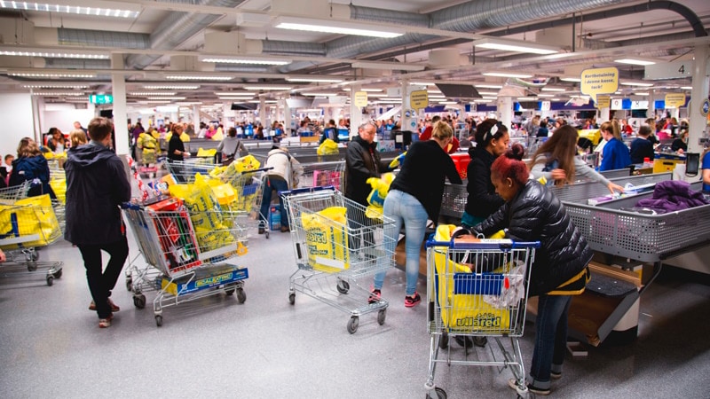 Des gens remplissent leur panier d’achats de sacs et d’articles qu’ils ont achetés à la caisse