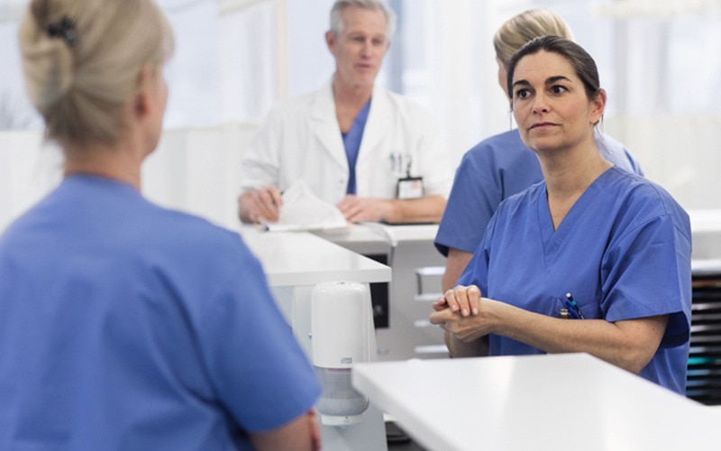 Enfermeras hablando, en el fondo un dispensador de jabón Tork y un médico hablando con otra enfermera