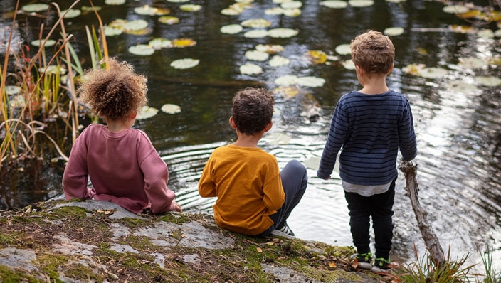 Three little boys sitting near a pond Three little boys sitting near a pond