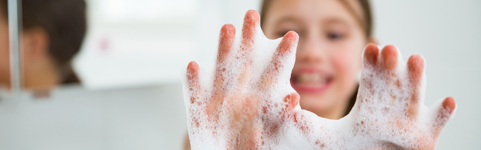 Manos de niña con espuma de jabón