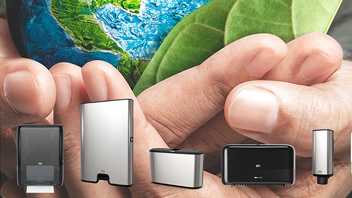 Hand holding the earth and some whit Tork dispensers in front