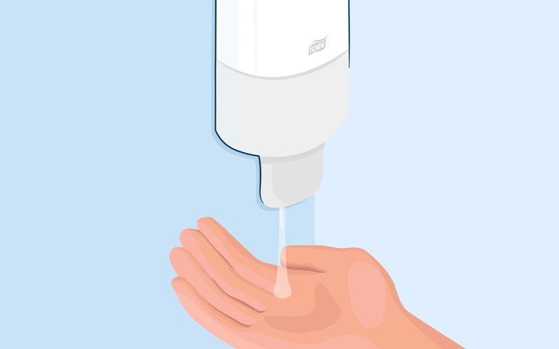 A drop of hand sanitizer falling onto a hand from a hand sanitizer dispenser.