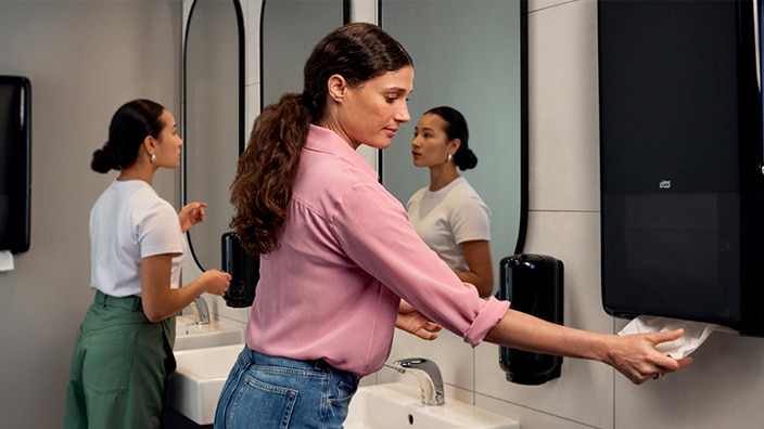 A person using a black Tork PeakServe dispenser