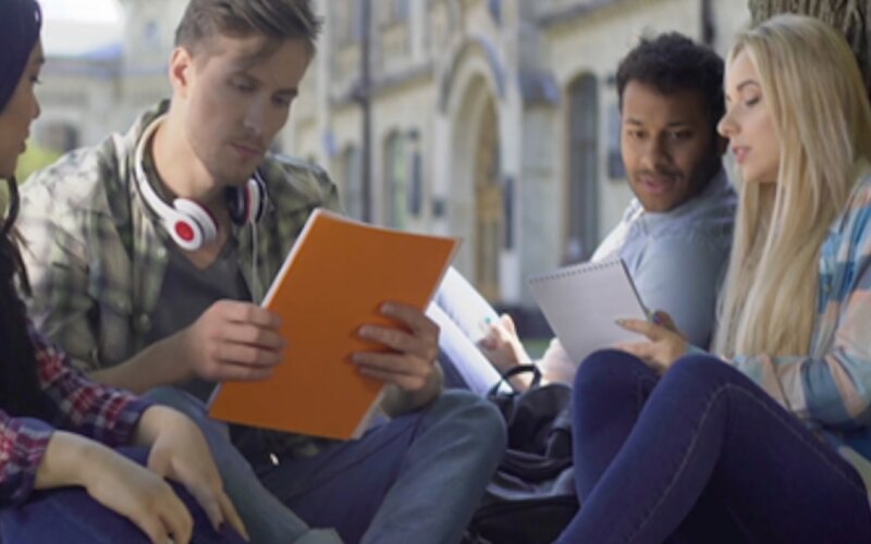 Groupe de personnes assises dehors en train de lire