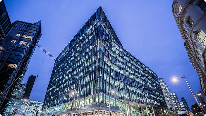 A modern glass office building illuminated at dusk. A modern glass office building illuminated at dusk.