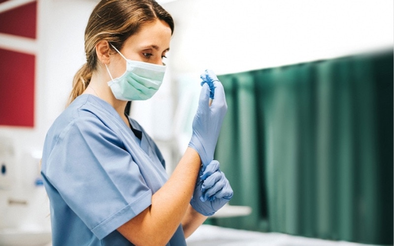 A nurse putting on blue plastic gloves