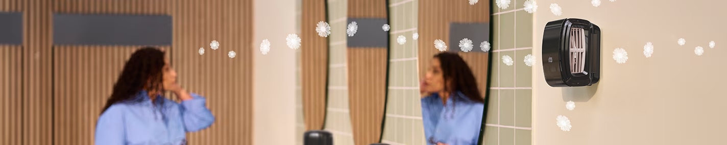 A woman standing in front of a mirror in a restroom A woman standing in front of a mirror in a restroom