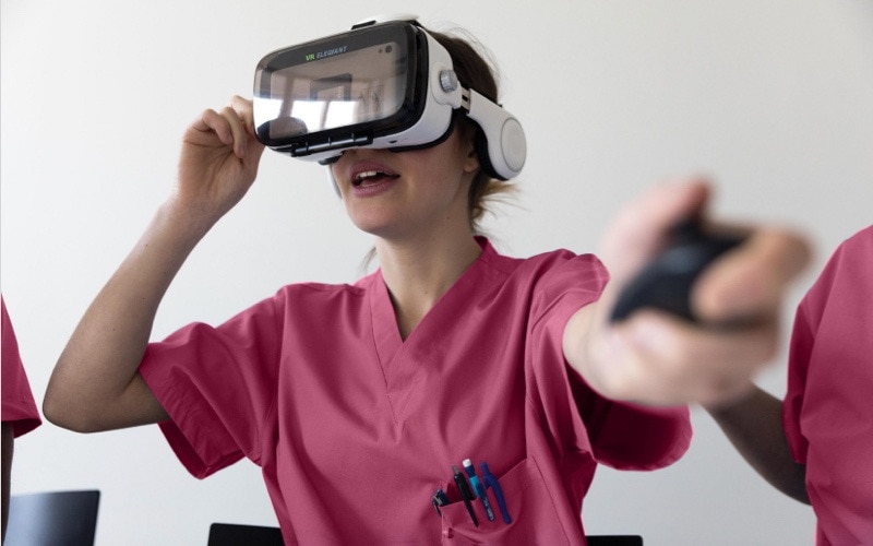 En sköterska i rosa arbetskläder som bär VR-headset