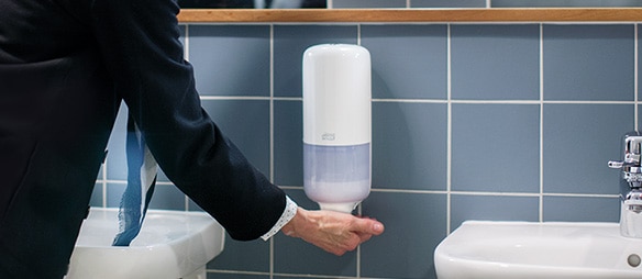 Older woman pushing soap dispenser​