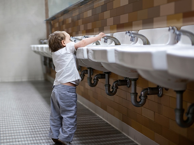 Young child plays with water from a hard to reach tap Young child plays with water from a hard to reach tap