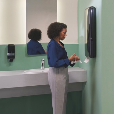 Woman taking a paper towel from a dispenser Woman taking a paper towel from a dispenser