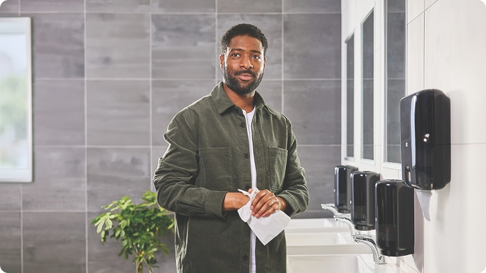 Person drying their hands in a modern restroom with multiple wallmounted dispensers Person drying their hands in a modern restroom with multiple wallmounted dispensers