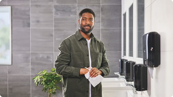Person drying their hands in a modern restroom with multiple wallmounted dispensers Person drying their hands in a modern restroom with multiple wallmounted dispensers