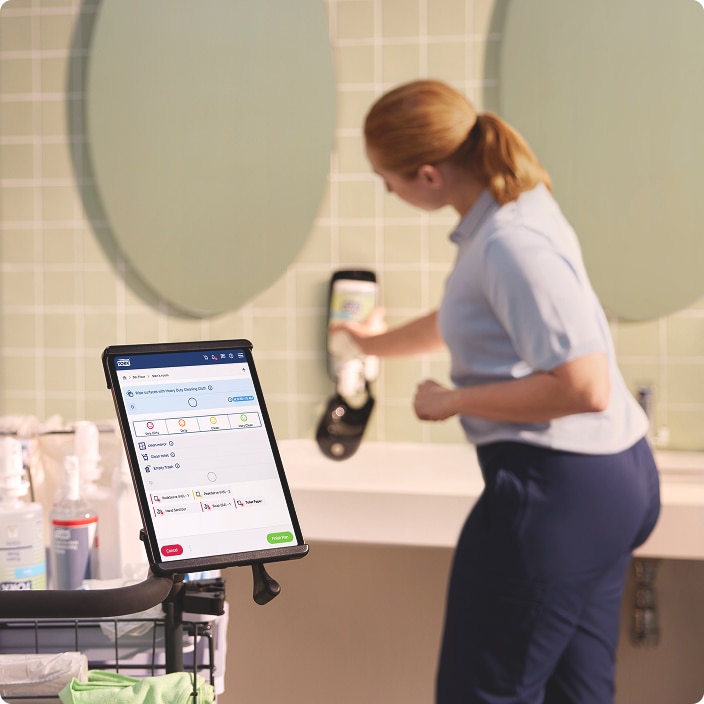 Cleaner refilling a soap dispenser while viewing task information on a tablet mounted to the cleaning cart Cleaner refilling a soap dispenser while viewing task information on a tablet mounted to the cleaning cart