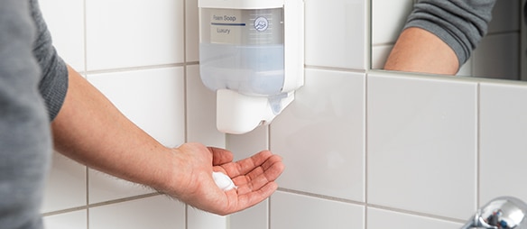 A person dispensing soap from a soap dispenser​