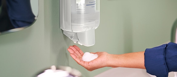 A person dispensing soap from a soap dispenser​