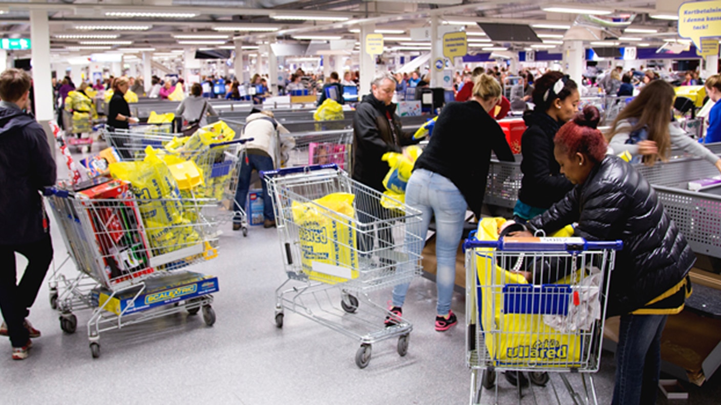 Folk som lastar kundvagnar vid kassorna i en livlig stormarknad