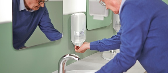 A man using a Tork Soap and Sanitiser Dispenser​