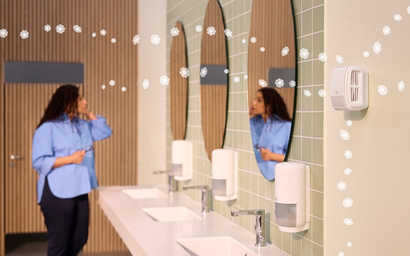 A woman standing in front of a mirror in a washroom