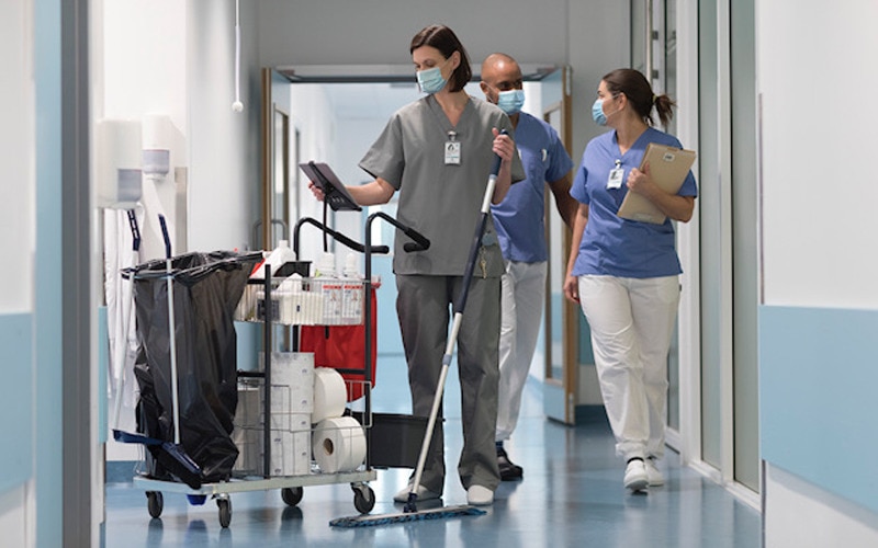Image of cleaner with trolley-mounted tablet looking showing the Tork Vision Cleaning interface