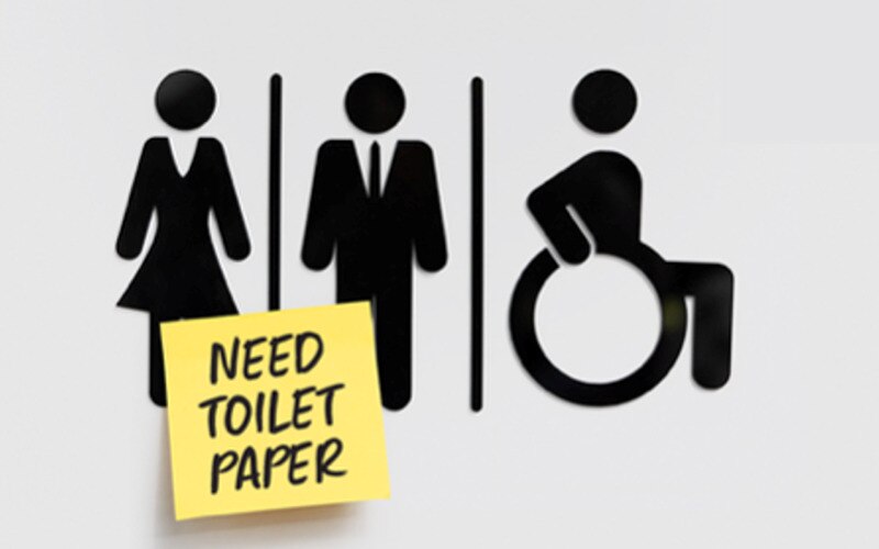 toalettskylt med symboler för herr, dam och rörelsehindrade personer, samt en post-it-lapp med texten ”toalettpapper behövs”