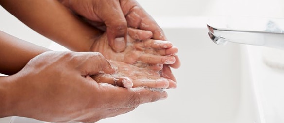 An adult washing a child's hands.