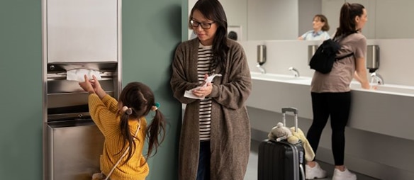 Child reaching for a paper hand towel in a washroom