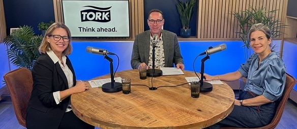 Podcastopname rond een tafel met drie personen en microfoons in een Tork‑studio.