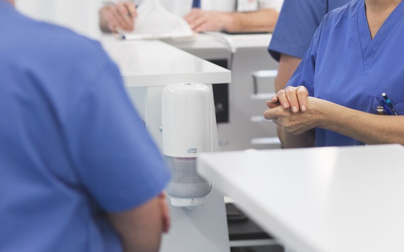 Woman sanitising her hands at a nurses station