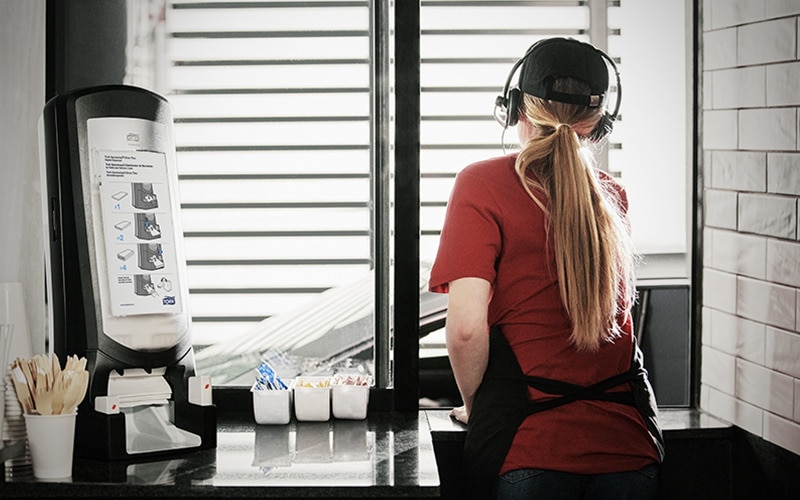 Kvinde der serverer gennem en restaurants drive-thru vindue
