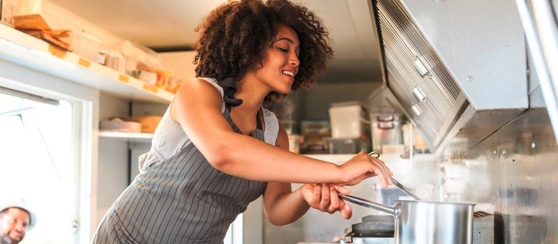 Une cheffe cuisine dans la cuisine d’un restaurant