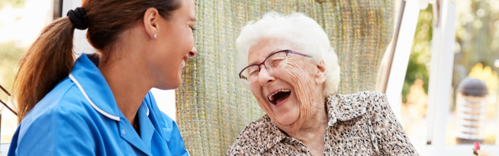 En sygeplejerske og en ældre kvinde griner sammen