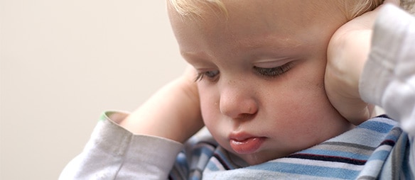 Young boy covering his ears due to loud noise​