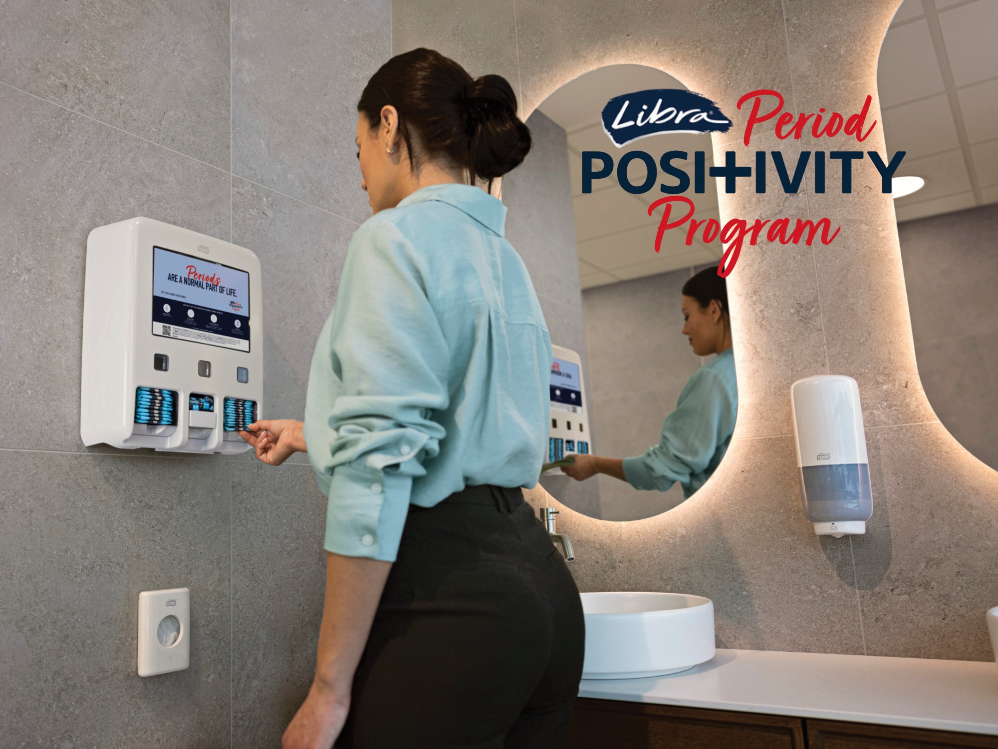 Woman taking pad from Libra Period Positivity Program dispenser Woman taking pad from Libra Period Positivity Program dispenser
