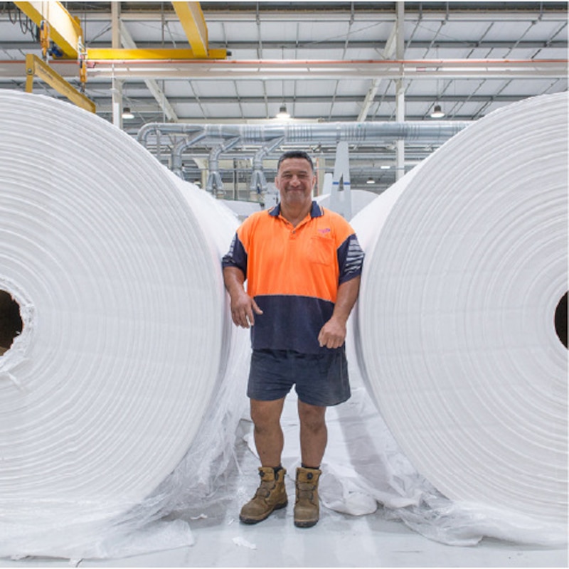 Kawerau staff standing next to reels of paper.