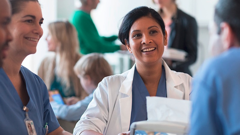 Doctors and nurses talking and laughing, sitting around a table in a canteen