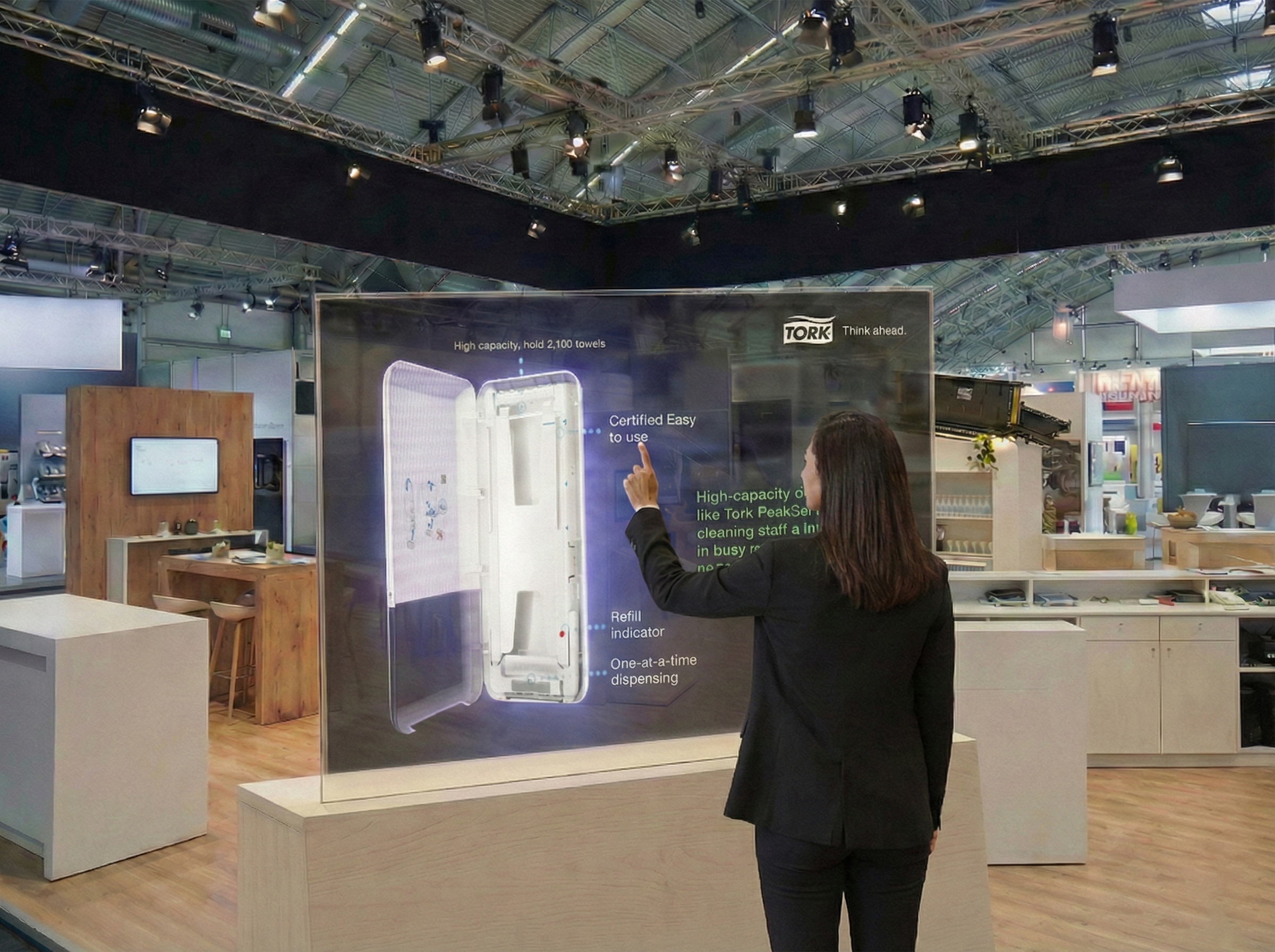 Woman at a trade show interacting with a digital touchscreen display featuring a Tork dispenser.