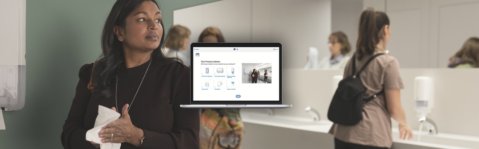 Women in a public washroom washing and drying their hands; in front, a laptop showing the Tork Product Advisor Tool