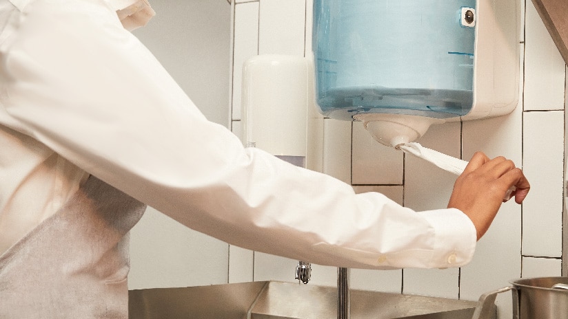 Woman pulling paper out of Tork Reflex Dispenser