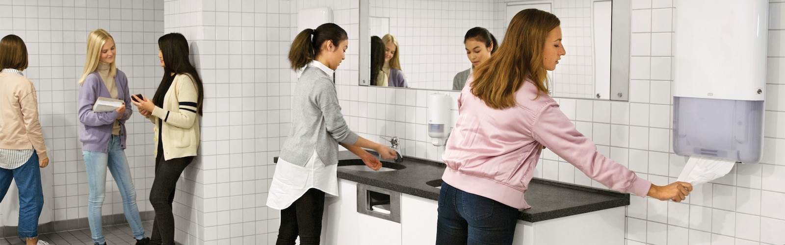 Person taking a paper hand towel from Tork PeakServe dispenser