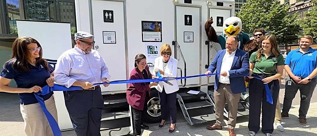 Ribbon cutting in front of portable restrooms